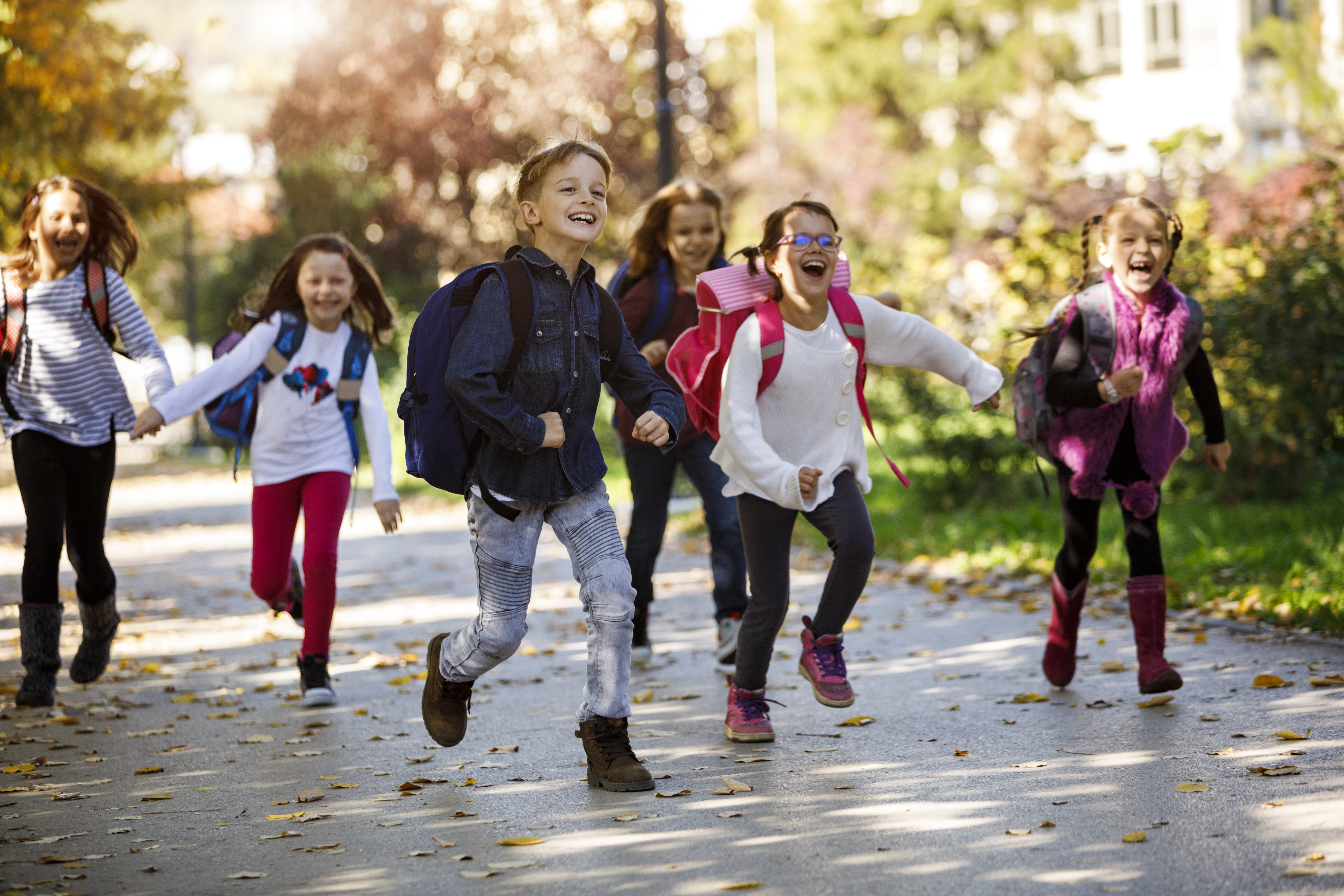 Young Comal ISD school kids with backpacks running outside after the end of the schoolday