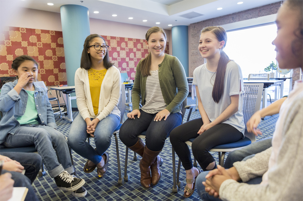 Smiling students from Smithson Valley Middle School having a round table discussion in a classroom