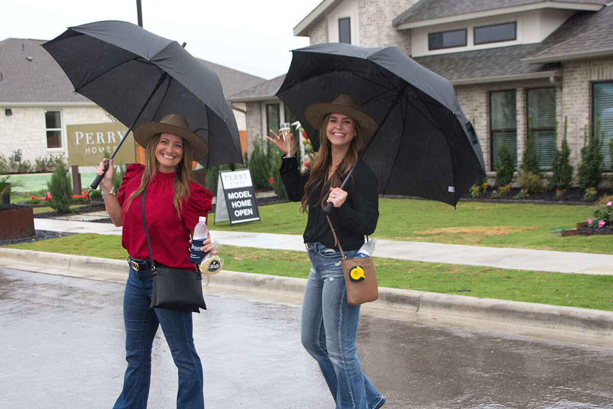 Two women posing with cowboy hats and umbrellas